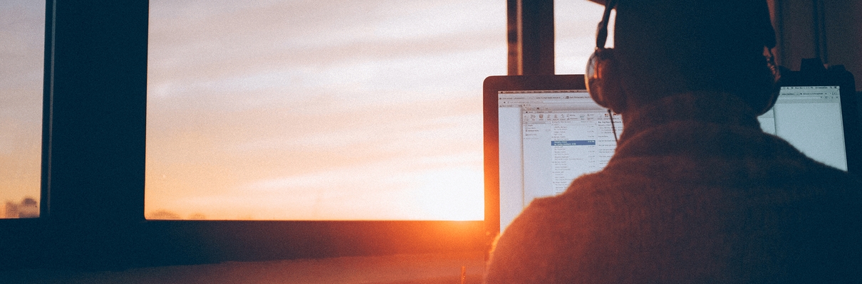 Image of man working at a computer in front of a window